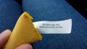 A fortune cookie, cracked open, with a fortune written in German visible.