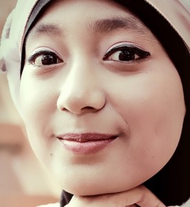 A woman wearing a hijab smiling at the camera.