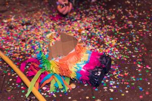 part of a smashed piñata lays on the ground among colourful confetti